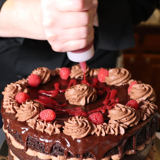 Chacha drizzling a raspberry coulis on a chocolate moose cake.